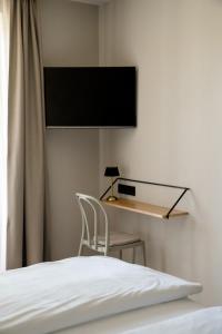 a bedroom with a bed and a desk with a television on the wall at Gasthof Thünauer in Offenhausen