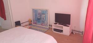 a bedroom with a bed and a flat screen tv at La Parenthèse d'Ouilly in Pont-d'Ouilly