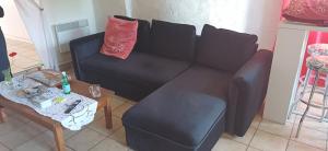 a living room with a black couch and a table at La Parenthèse d'Ouilly in Pont-d'Ouilly