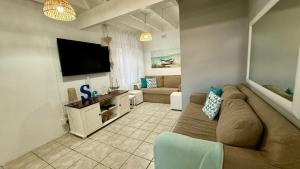 a living room with a couch and a flat screen tv at Karlin #2, Frontline, Beach Access, Scottburgh in Freeland Park
