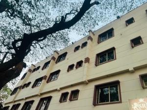 a building with many windows in front of a tree at Sahara Residency Mysore in Mysore
