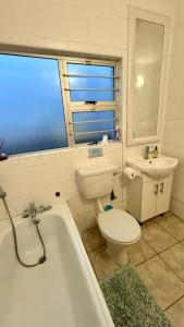 a bathroom with a toilet and a tub and a sink at Karlin #2, Frontline, Beach Access, Scottburgh in Freeland Park +32 photos