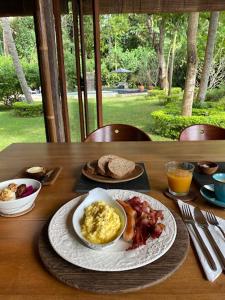 a table with a breakfast of eggs bacon and toast at HIDDEN HEAVEN Rumah Barong in Jasri