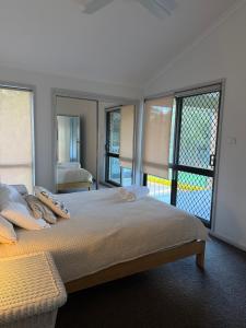 a bedroom with a large bed with a large window at Coconuts - 3 bedroom 3 bathroom townhouse with tennis court in Nelson Bay