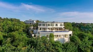 a large white house in the middle of trees at Villa Aventus Uluwatu in Uluwatu +23 photos