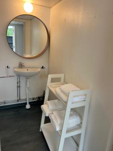 a bathroom with a sink and a shelf with towels at 'Ekhaga Cabins' Lillestugan in Viddviken