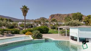 a swimming pool in a resort with mountains in the background at Hotiday Vulcano Porto in Vulcano