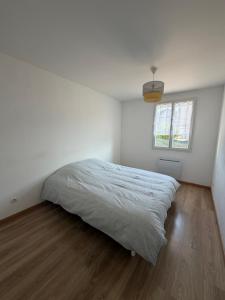 a white bedroom with a bed and a window at La Parenthèse Immo in Amilly