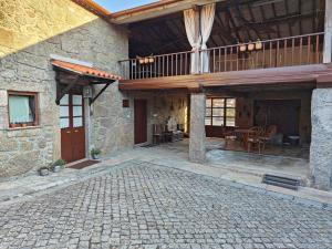 a stone house with a balcony and a patio at Casa do Muro Alto in Alvelos