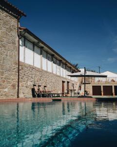 a swimming pool in front of a stone building at Casa do Muro Alto in Alvelos