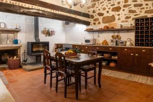 a kitchen with a table and chairs and a fireplace at Casa do Muro Alto in Alvelos
