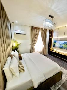 a bedroom with a large white bed and a chandelier at Luxury 2BR Oasis in Lekki +15 photos