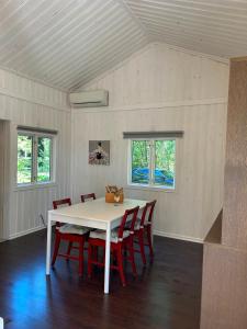 a dining room with a white table and red chairs at 'Ekhaga Cabins' Lillestugan in Viddviken