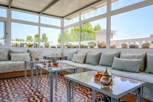 a living room with couches and tables and windows at Riad Salt River in Martil