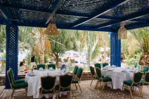 a dining room with white tables and green chairs at Rive Du Lac in Lalla Takerkoust