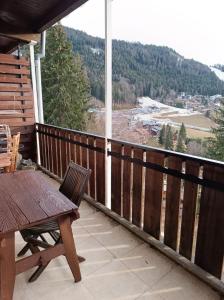 a deck with a table and chairs on a balcony at Bel Appartement panoramique in Arâches-la-Frasse