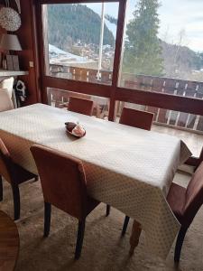 a table and chairs in a room with a large window at Bel Appartement panoramique in Arâches-la-Frasse +7 photos
