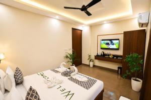 a bedroom with two beds and a flat screen tv at Sunburry Hotel Tapovan Rishikesh in Narendranagar
