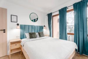 a bedroom with a bed with blue curtains and a window at Enjoy! Piaseczno in Piaseczno
