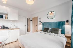 a white bedroom with a bed and a kitchen at Enjoy! Piaseczno in Piaseczno