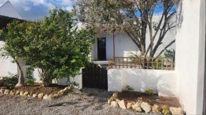 a white house with two trees and a fence at Harts Water in Jacobs Bay