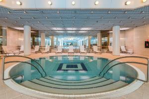 a large pool in a lobby with chairs and tables at Hotel Aro Palace in Braşov