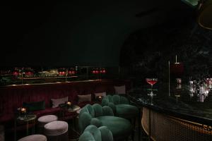 a bar with green chairs and a table with a glass of wine at Eurostars Josefine in Vienna