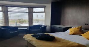 a bedroom with a bed and chairs and a window at South Beach Kings Promenade Hotel in Blackpool