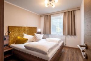 a hotel room with a bed with white sheets and pillows at Apart Denise in Fügen