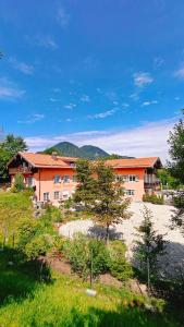 an orange building with trees in front of it at Hotel Garni Forsthaus Ruhpolding incl Chiemgau Karte in Ruhpolding