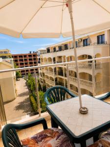 a table and chairs with an umbrella on a balcony at Hotel Topalovi in Nesebar