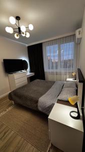 a bedroom with a bed and a flat screen tv at Compass Apartments Елітний Житловий комплекс in Chernivtsi