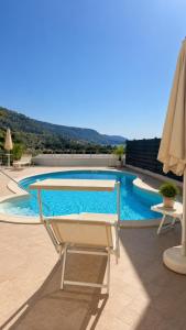 a swimming pool with a chair and an umbrella at Glory Guest House Sea View in Mandaradoni