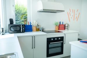 a white kitchen with a stove and a microwave at Cool Cool House in Liège