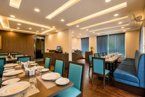 a restaurant with a long table and blue chairs at Ramatan Resort in Vagator +18 photos
