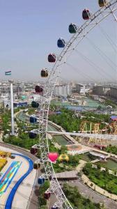 a ferris wheel in a park with a city at Afsona in Namangan