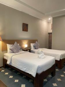 a hotel room with two beds with white sheets at Margot Guest House in Sanur
