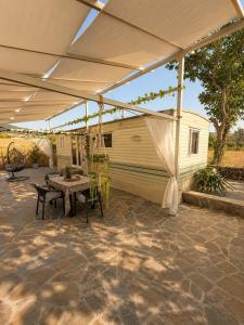 a patio with a tent and a table and a building at Glykofilousa Tiny Ηouse in Petra