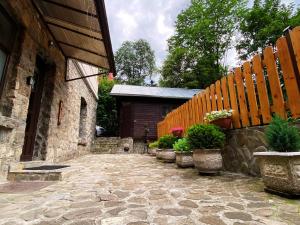a stone pathway with potted plants and a wooden fence at The Stone Garden Apartment - free parking, private yard in Sinaia
