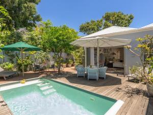 a backyard with a swimming pool and a table and umbrella at Himmelblau Boutique Bed and Breakfast in Cape Town