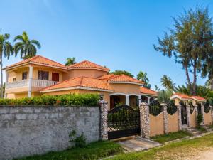 a house with a fence and palm trees at Elegant Villa in Nagua with Private Pool and Jacuzzi in Nagua