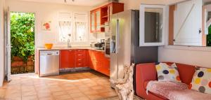 a kitchen with orange cabinets and a red couch at Villa ensoleillée aux Anses-d'Arlet avec piscine privée in Les Anses-dʼArlets