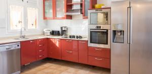a kitchen with red cabinets and a stainless steel refrigerator at Villa ensoleillée aux Anses-d'Arlet avec piscine privée in Les Anses-dʼArlets