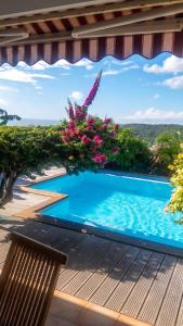 a pool on the deck of a house with flowers at Villa ensoleillée aux Anses-d'Arlet avec piscine privée in Les Anses-dʼArlets +20 photos