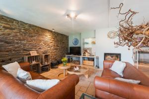a living room with leather furniture and a brick wall at Une parenthèse en Ardenne in Nollevaux