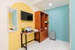 a room with a desk with a computer and a tv at Sans Hotel Sedana Batam in Nagoya