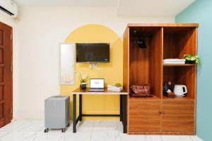 a room with a desk with a tv and a cabinet at Sans Hotel Sedana Batam in Nagoya