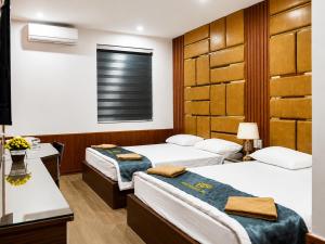 a hotel room with three beds and a window at Ruby 25 Hotel in Hà Ðông