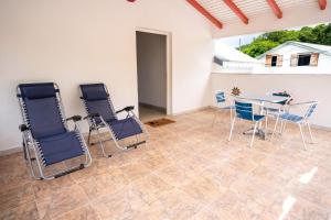 a patio with chairs and a table and a table at Maison vue sur mer à Vieux-Habitants + Terrasse in Vieux-Habitants