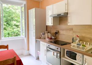 a small kitchen with white cabinets and a window at Appartement cosy à Néris-les-Bains, 20 m², balcon avec vue in Néris-les-Bains